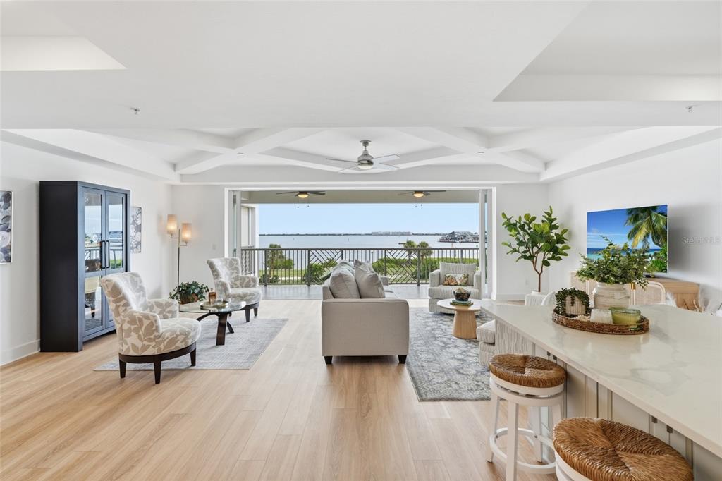 A bright, open-concept living room features light wood floors, coffered ceilings, and a large balcony — 1425 PARK BEACH CIRCLE UNIT 1310, PUNTA GORDA, FL