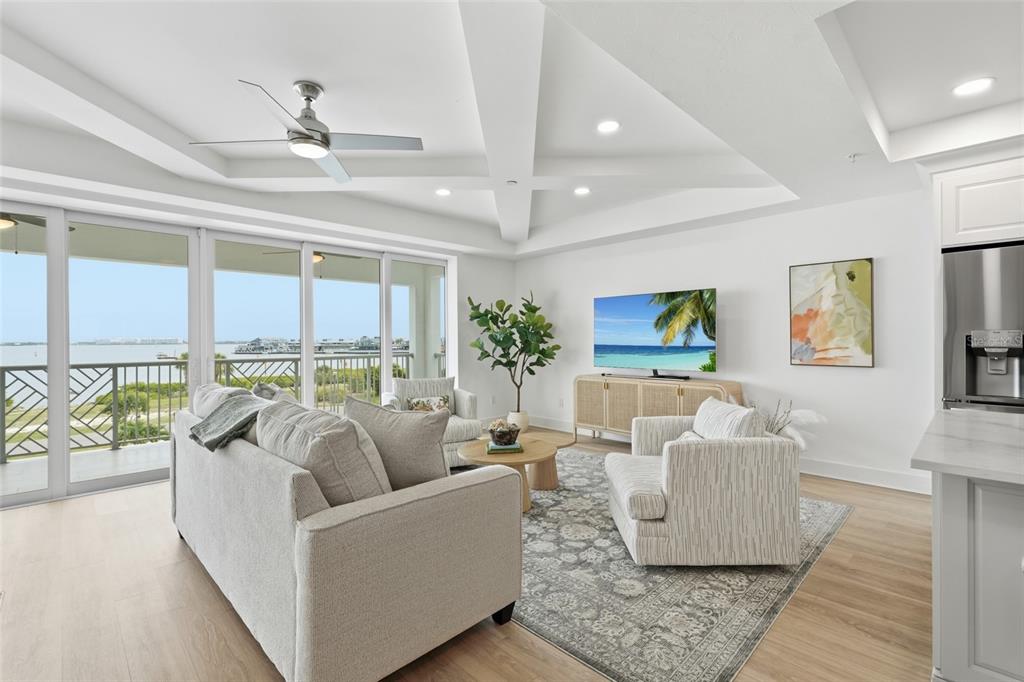 A living room features a coffered ceiling, light wood floors, and a balcony overlooking water — 1425 PARK BEACH CIRCLE UNIT 1310, PUNTA GORDA, FL