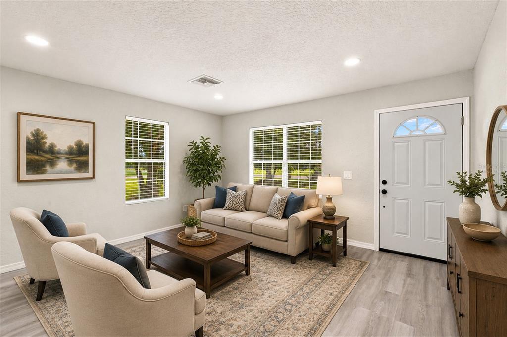 A living room features light-colored walls, wood-look flooring, a sofa, two armchairs, and a front door — 2419 SW HILLSBOROUGH AVENUE, ARCADIA, FL