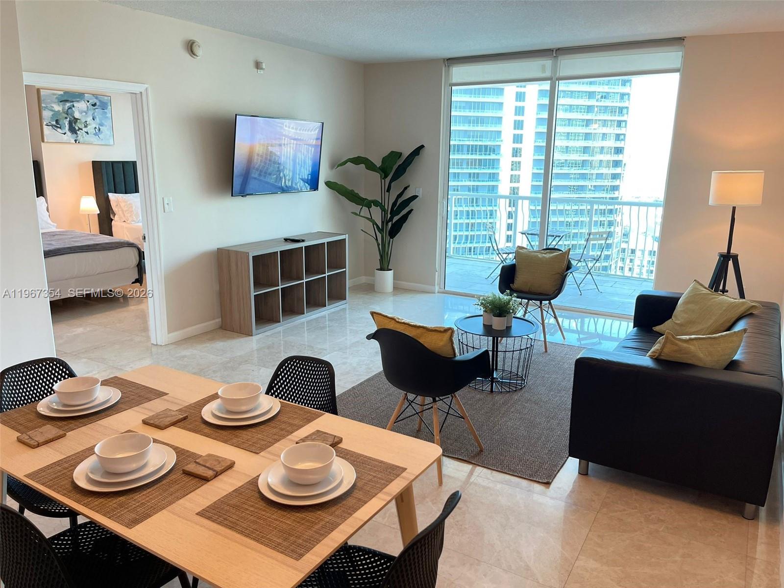 A modern living and dining area features tile floors, a balcony, and city views — 1200 Brickell Bay Dr # 4217, Miami FL 33131, MIAMI, FL