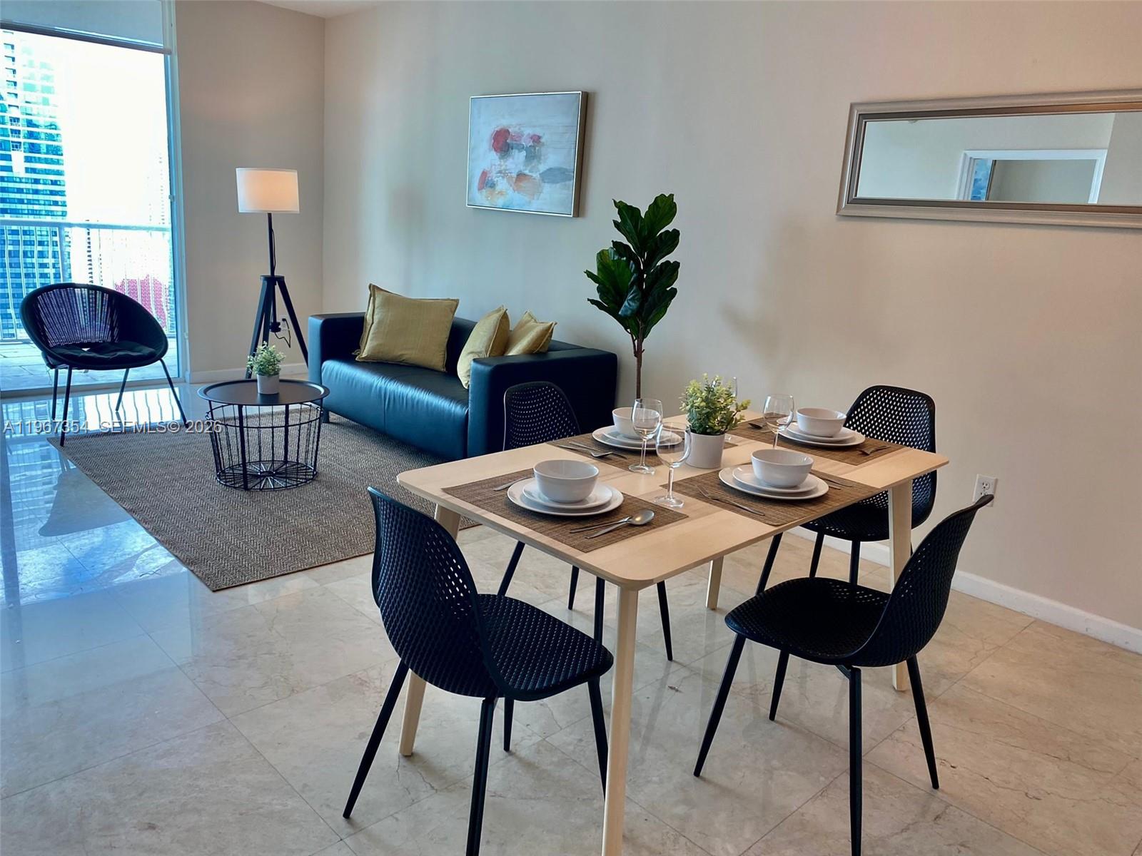 A modern apartment living and dining area features a sofa, dining set, and balcony view — 1200 Brickell Bay Dr # 4217, Miami FL 33131, MIAMI, FL
