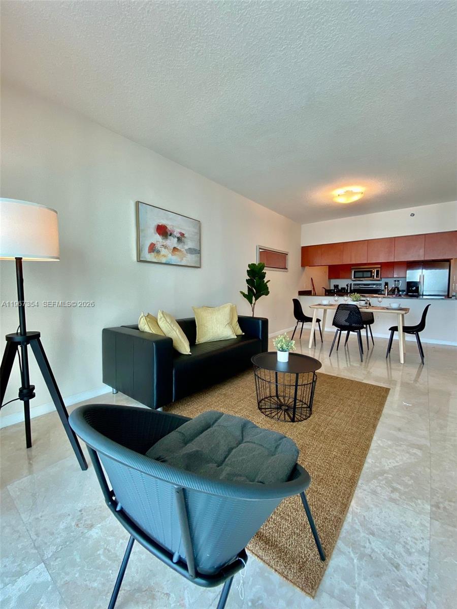 A living room with a black sofa, a dining area, and tile flooring — 1200 Brickell Bay Dr # 4217, Miami FL 33131, MIAMI, FL