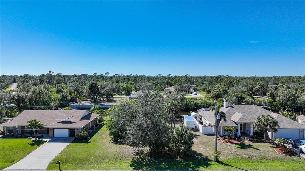 An aerial view shows two suburban houses with driveways and lawns near a wooded area — 3455 MONTGOMERY DRIVE, PORT CHARLOTTE, FL
