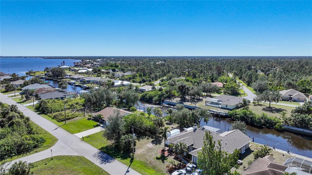 An aerial view shows a residential neighborhood with houses, a canal, and surrounding trees — 3455 MONTGOMERY DRIVE, PORT CHARLOTTE, FL