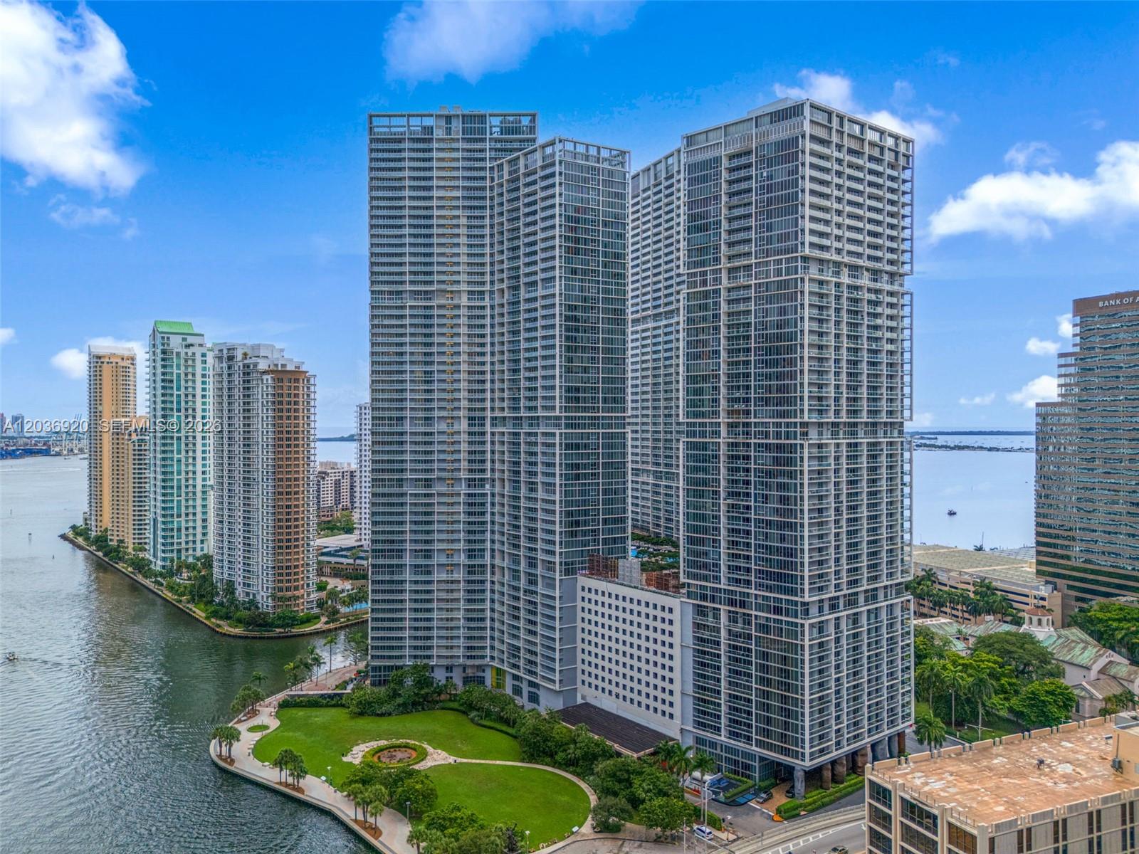 An aerial view shows several tall glass skyscrapers situated along a waterfront park and canal — 495 Brickell Ave # 905, Miami FL 33131, MIAMI, FL