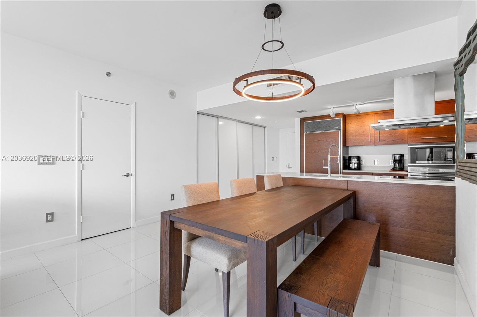 A dining area with a wooden table and bench sits adjacent to a modern kitchen — 495 Brickell Ave # 905, Miami FL 33131, MIAMI, FL