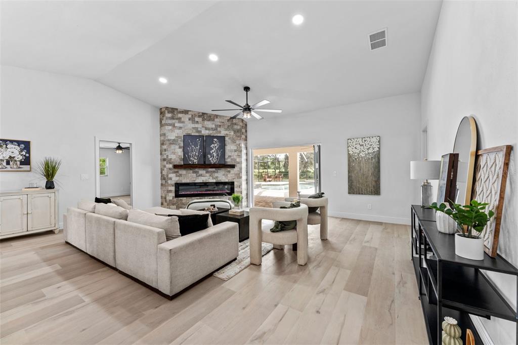 A living room features a stone fireplace, light wood flooring, and a large sectional sofa — 10204 TRANQUIL LANE, ODESSA, FL