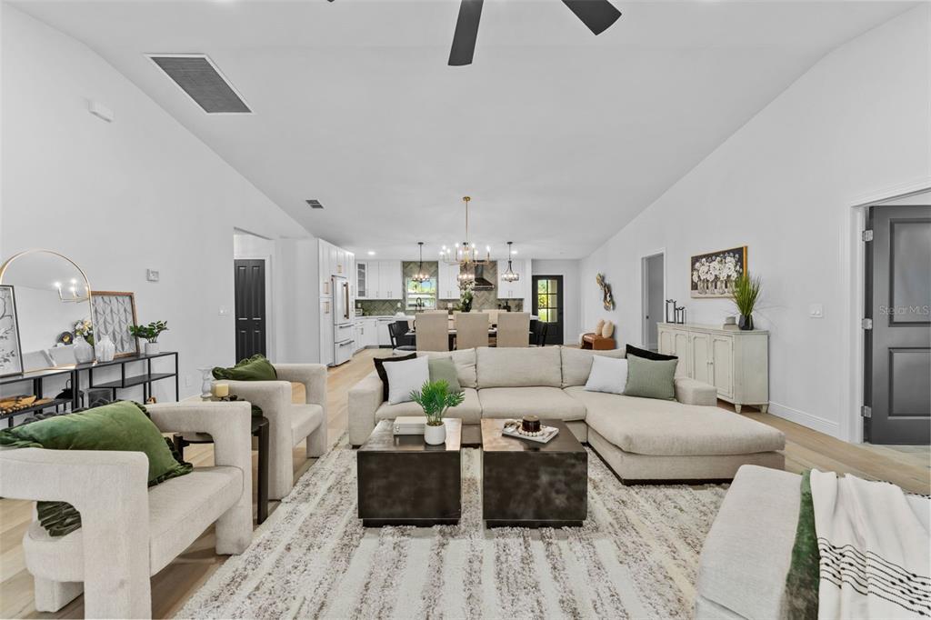 A spacious open-concept living room features a large sectional sofa, neutral decor, and hardwood floors — 10204 TRANQUIL LANE, ODESSA, FL