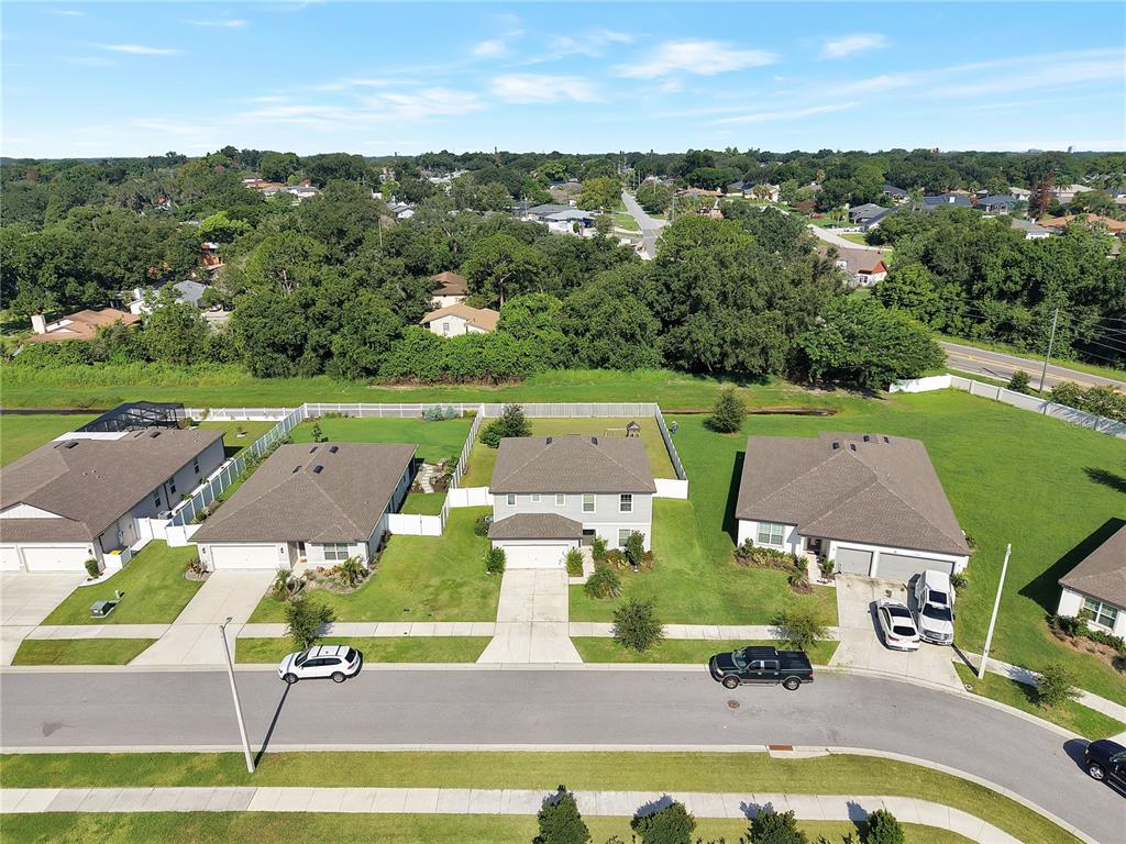 An aerial view shows three suburban houses with driveways and lawns along a curved street — 1042 MICHELANGELO LANE, WINTER HAVEN, FL