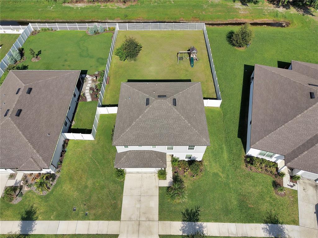 An aerial view shows a suburban house with a fenced backyard and a driveway — 1042 MICHELANGELO LANE, WINTER HAVEN, FL