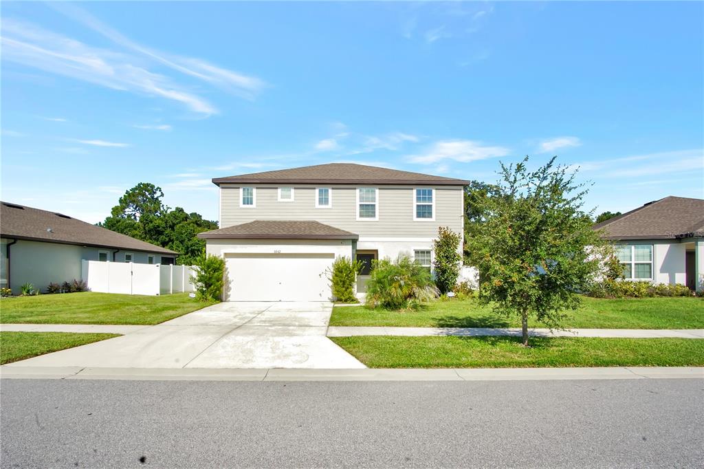 A two-story suburban house with a light-colored exterior, a two-car garage, and a front lawn — 1042 MICHELANGELO LANE, WINTER HAVEN, FL