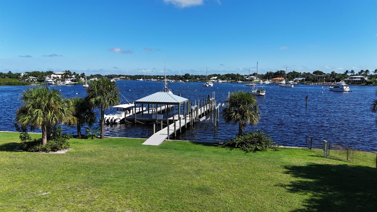 A grassy lawn leads to a private boat dock with a covered slip on water — 4345 SE Mulford Lane, Stuart FL 34997, STUART, FL