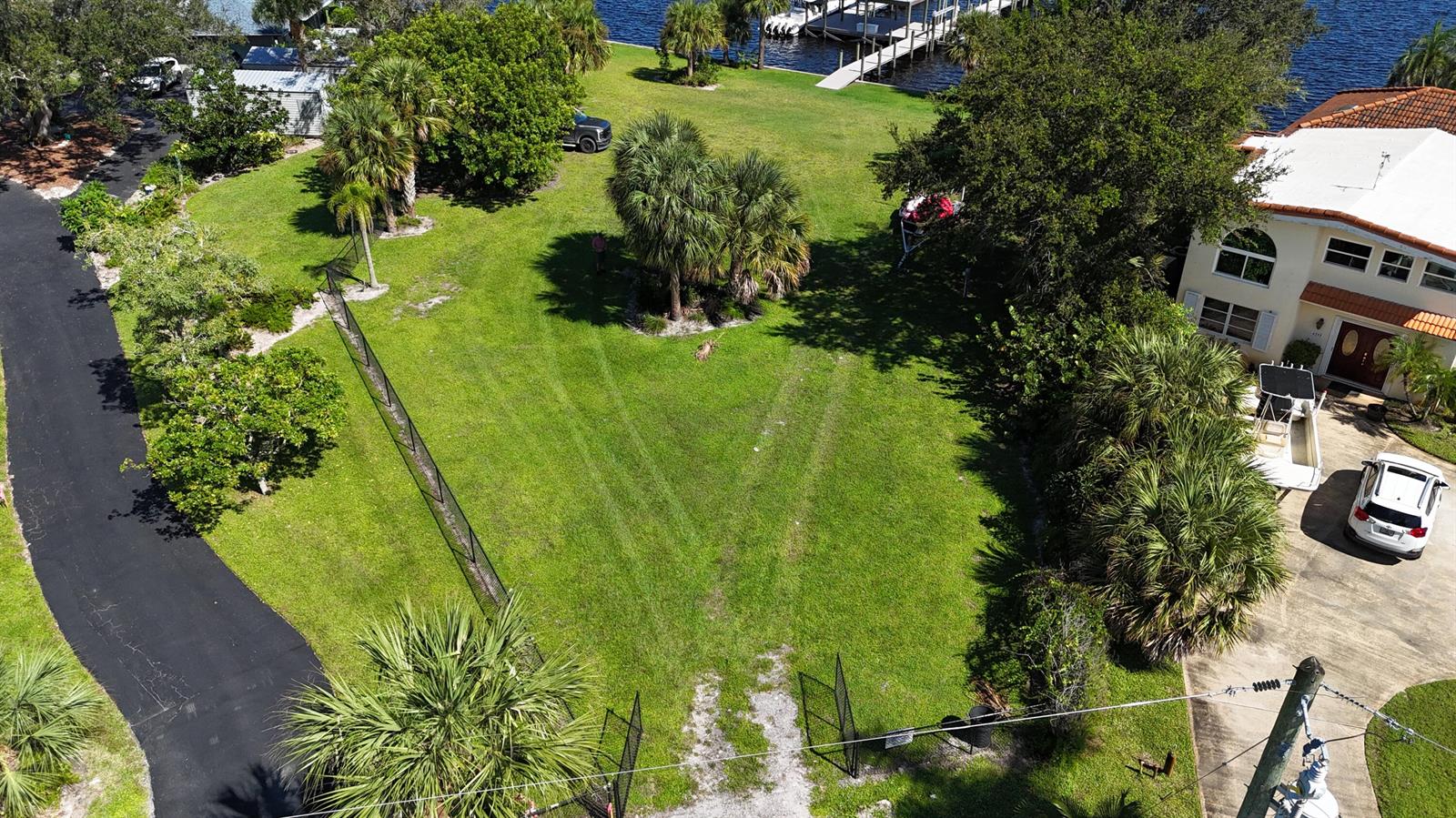 An aerial view shows a grassy lot with palm trees, a driveway, and a house — 4345 SE Mulford Lane, Stuart FL 34997, STUART, FL
