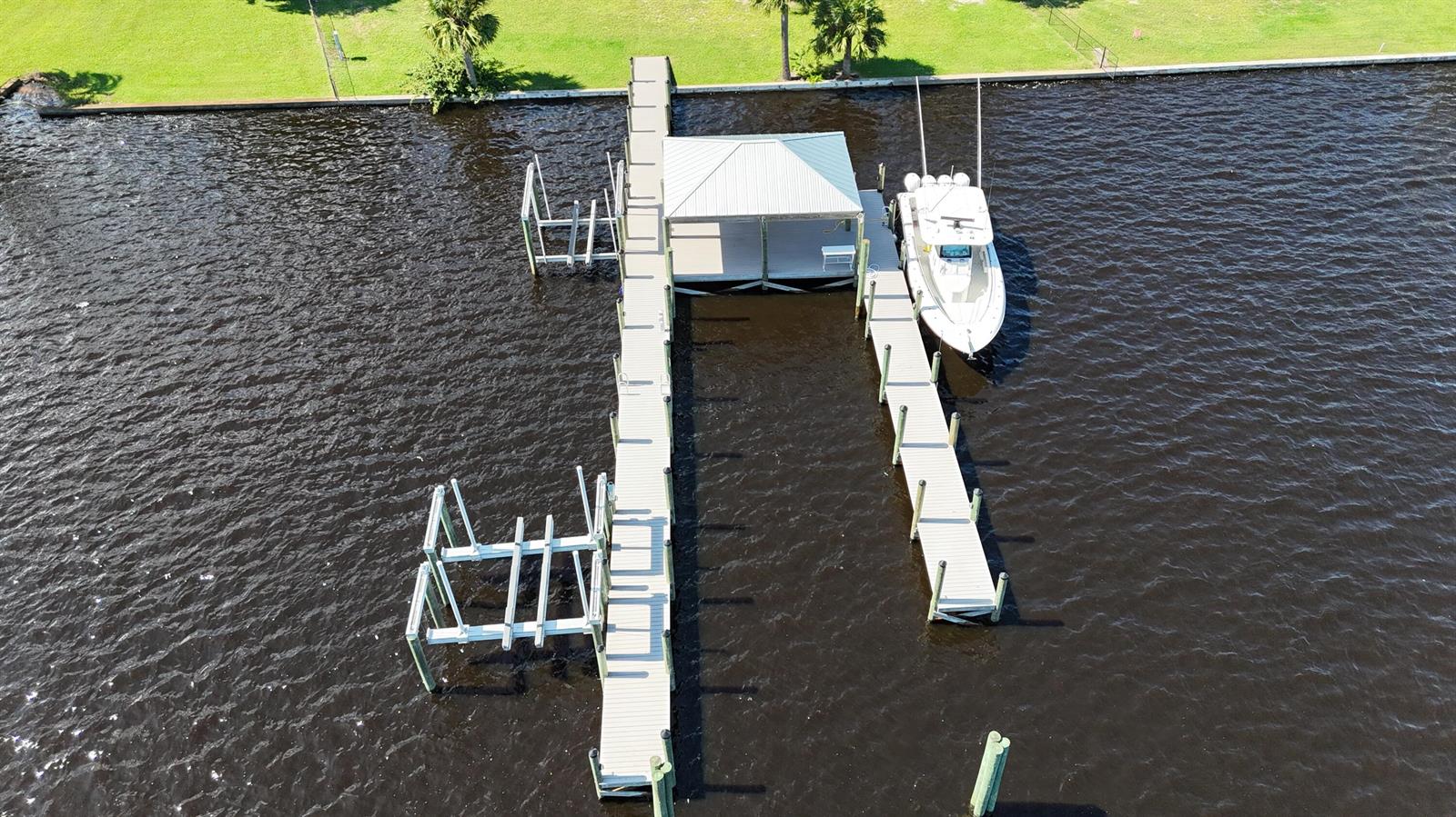 An aerial view shows a wooden dock with a covered boat slip and boat lift — 4345 SE Mulford Lane, Stuart FL 34997, STUART, FL
