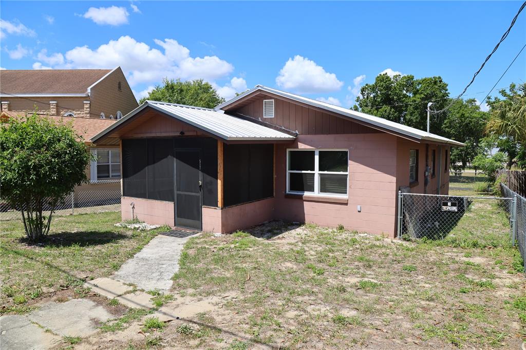 A single-story house with a screened-in porch, metal roof, and pink exterior walls — 517 HARRIS STREET, SEBRING, FL