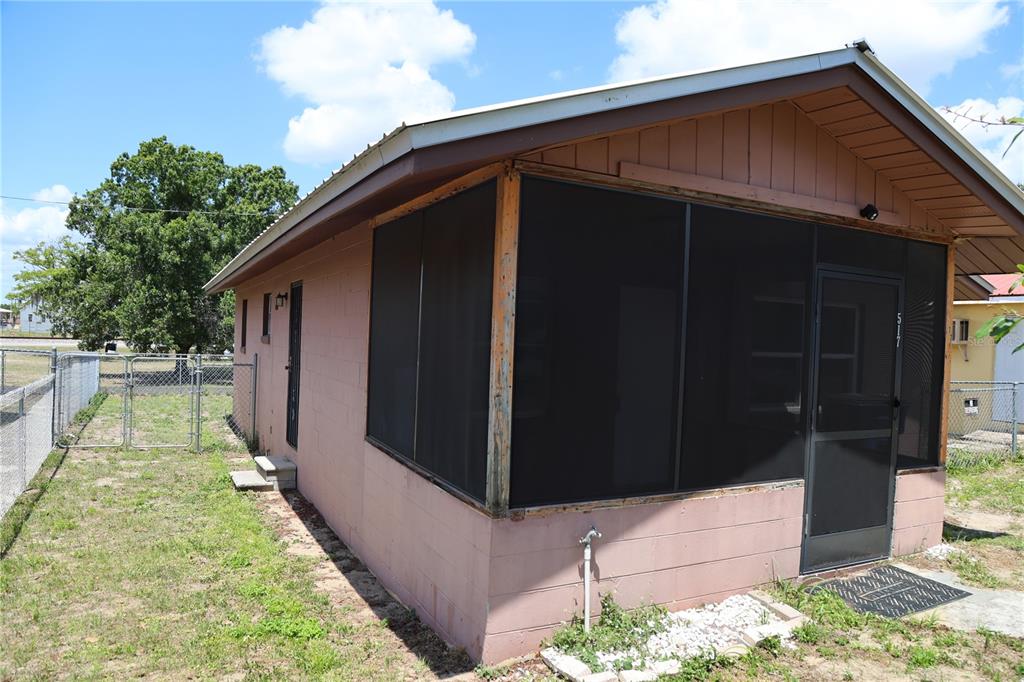 A pink concrete block house features a screened-in porch and a metal roof — 517 HARRIS STREET, SEBRING, FL