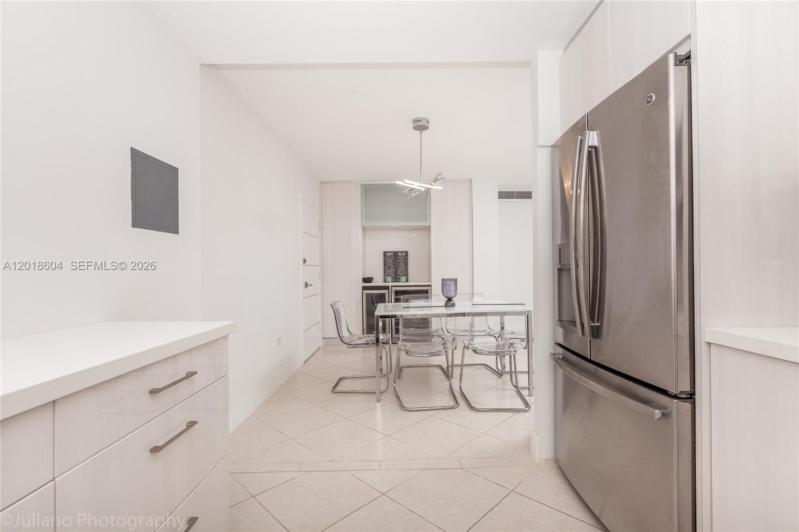 A modern kitchen features white cabinetry, stainless steel appliances, and a glass dining table — 5555 Collins Ave # 9U, Miami Beach FL 33140, MIAMI BEACH, FL