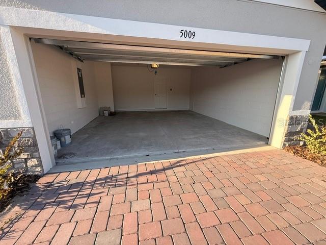 An open garage with a concrete floor and a brick paver driveway — 5009 KAIA AVENUE, WINTER HAVEN, FL