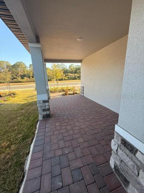 A covered entryway features a brick paver floor, a stucco wall, and stone pillar accents — 5009 KAIA AVENUE, WINTER HAVEN, FL