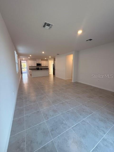 An open-concept living area features light-colored tile flooring and a kitchen with white cabinetry — 5009 KAIA AVENUE, WINTER HAVEN, FL