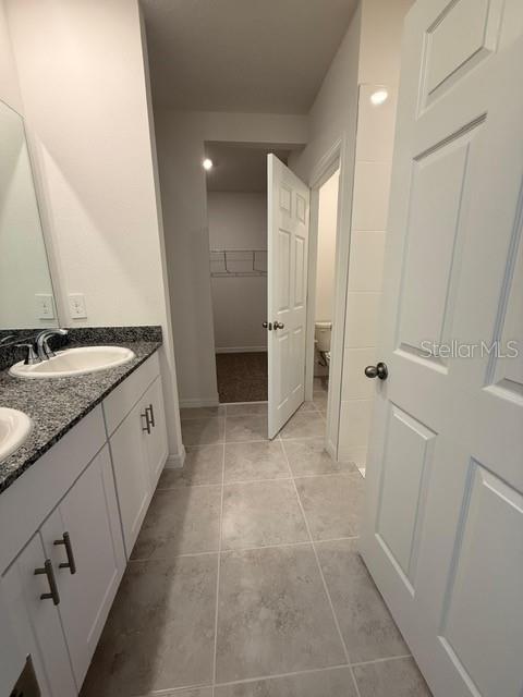 A bathroom features a granite vanity, white cabinets, tile flooring, and a walk-in closet — 5009 KAIA AVENUE, WINTER HAVEN, FL