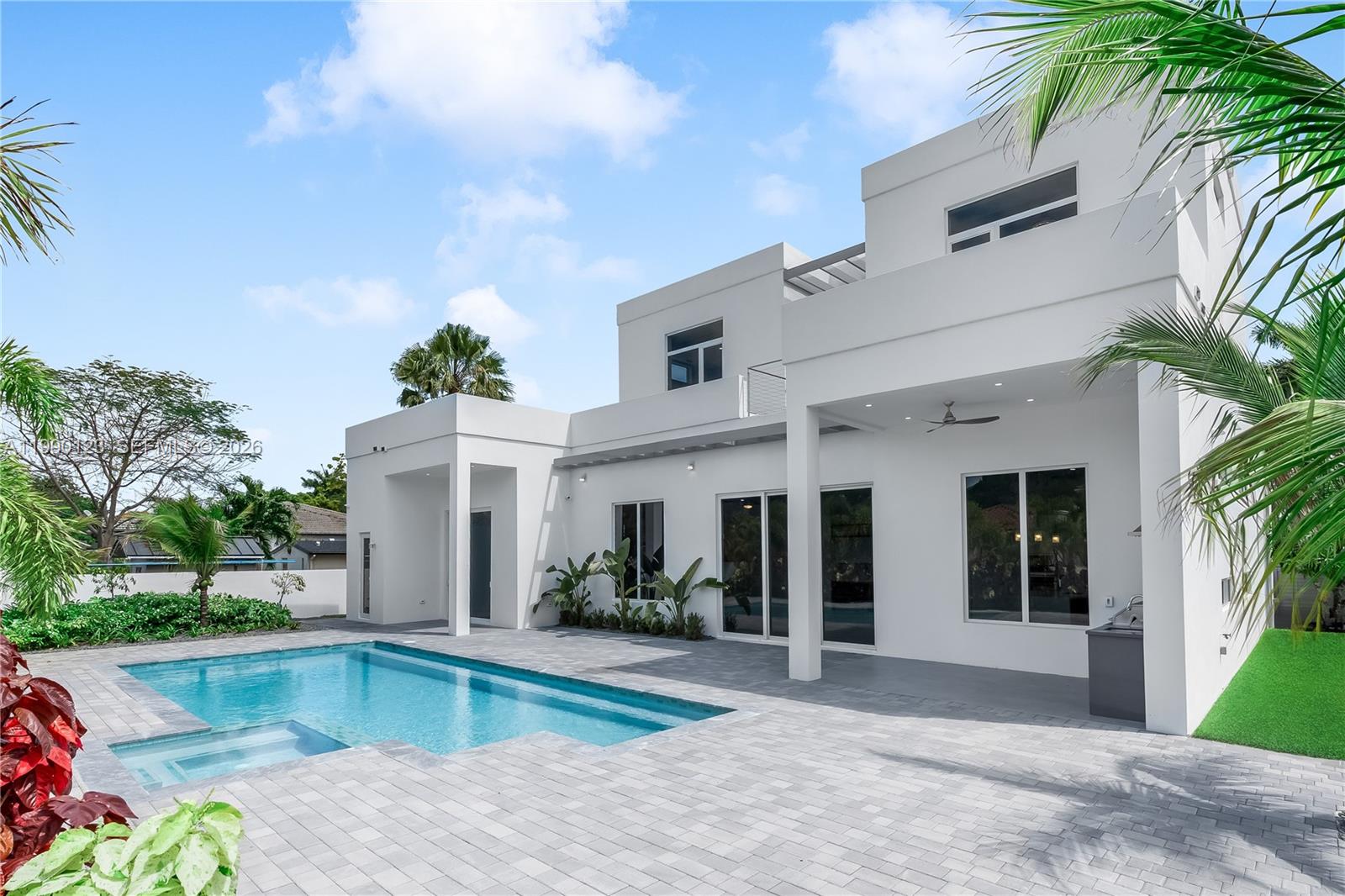 A modern white two-story house with a swimming pool and paved patio area — 9895 NW 26th St, Doral FL 33172, DORAL, FL