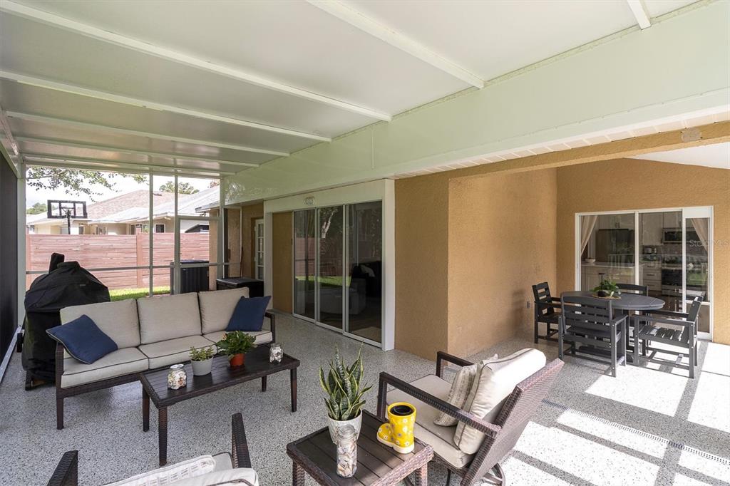 A covered patio with a speckled floor, outdoor furniture, and a screened-in enclosure — 7832 BLUE SPRING DRIVE, LAND O LAKES, FL