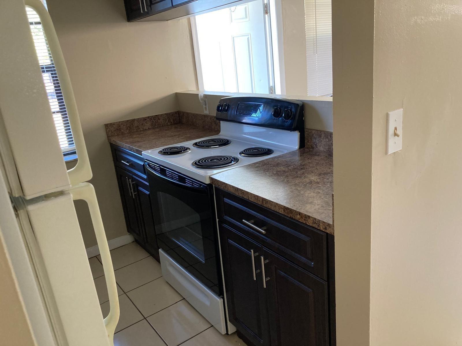 A kitchen features dark wood cabinets, laminate countertops, a white electric stove, and tile flooring — 6148 SW 35th Street # 3, Miramar FL 33023, MIRAMAR, FL