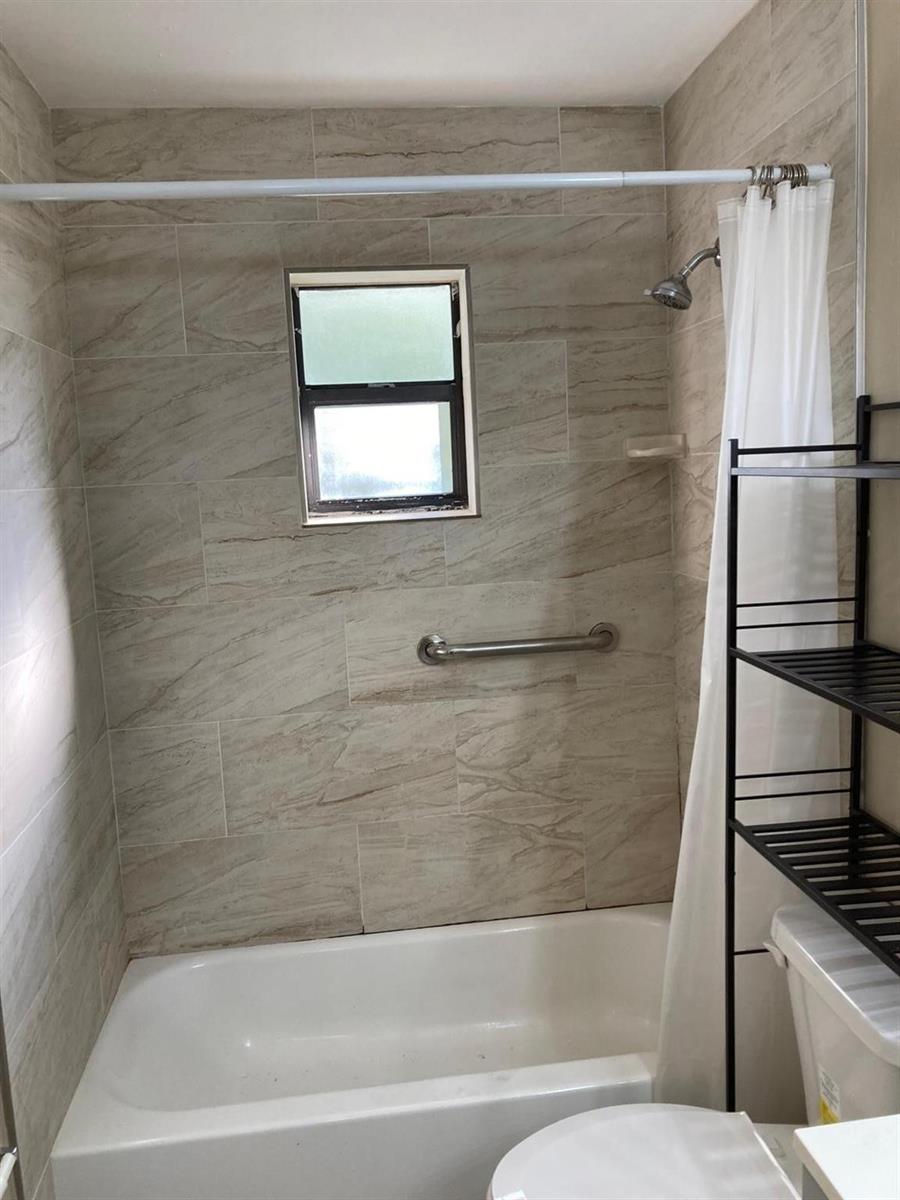A bathroom features a white bathtub, a showerhead, a grab bar, and beige tiled walls — 6148 SW 35th Street # 3, Miramar FL 33023, MIRAMAR, FL