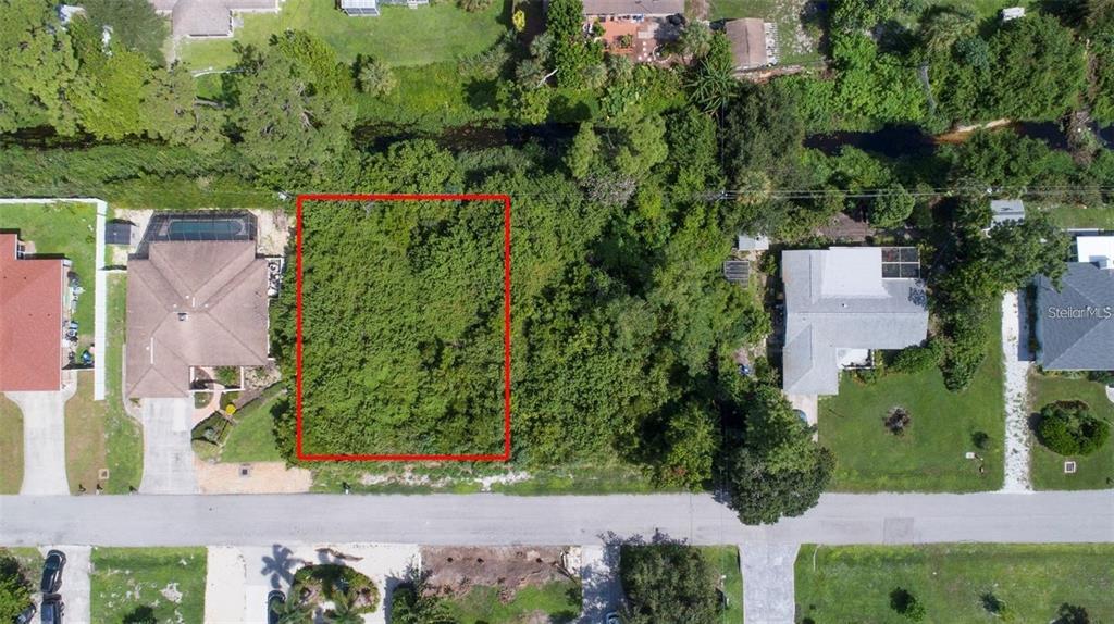 An aerial view shows a vacant, wooded residential lot outlined in red between two houses — MISSOURI ROAD, VENICE, FL