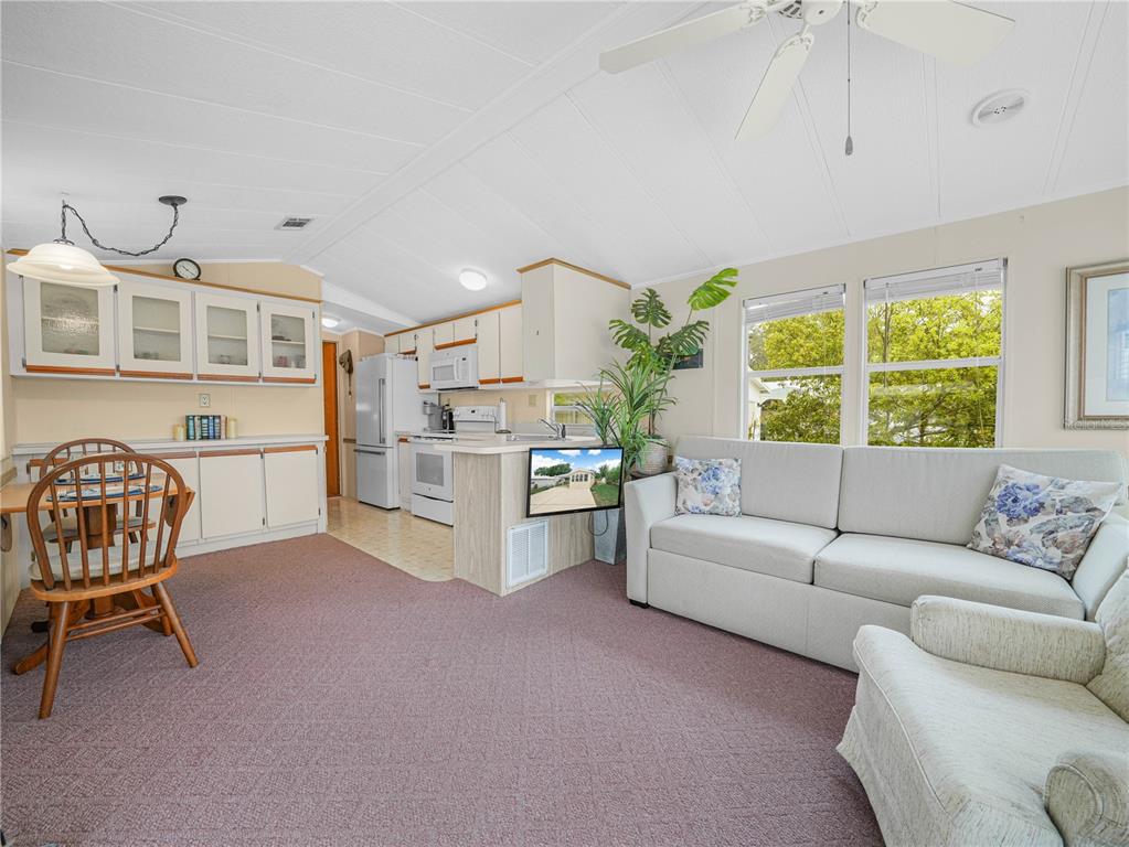 A living room and kitchen area with carpeted floors, white cabinets, and a sofa — 6 SILVERSIDES STREET, LAKE WALES, FL