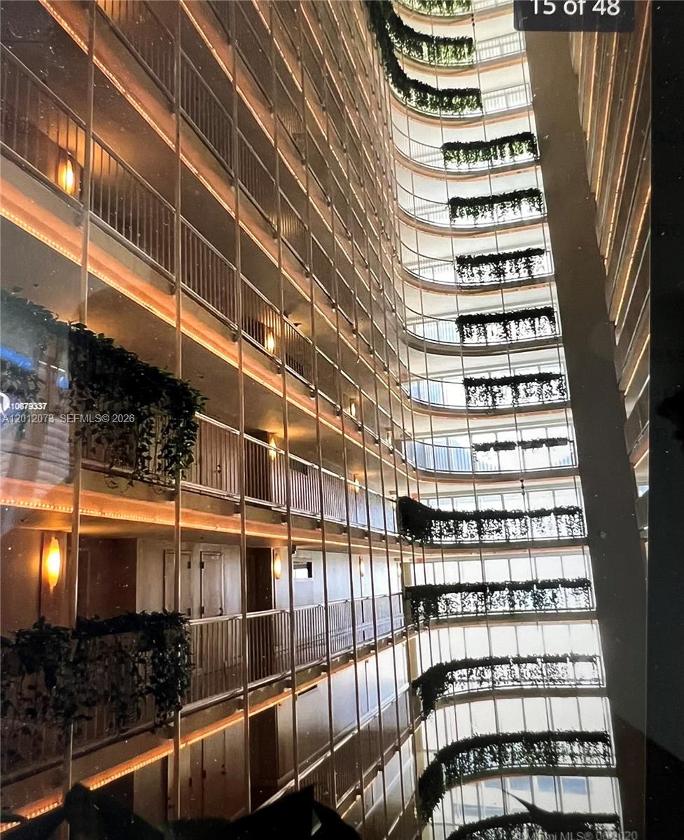 A view looking down into the multi-story atrium of a building with hanging balcony plants — 1717 N Bayshore Dr # A1448, Miami FL 33132, MIAMI, FL