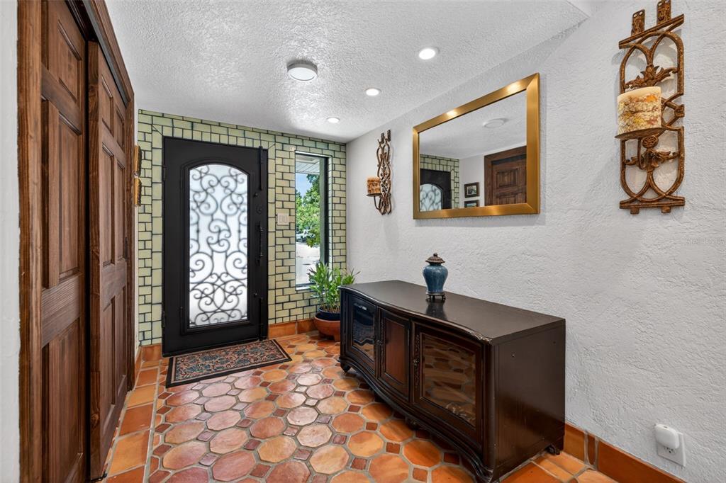 An entryway features a tiled floor, a dark wood console table, and a decorative front door — 6213 12TH AVENUE S, GULFPORT, FL