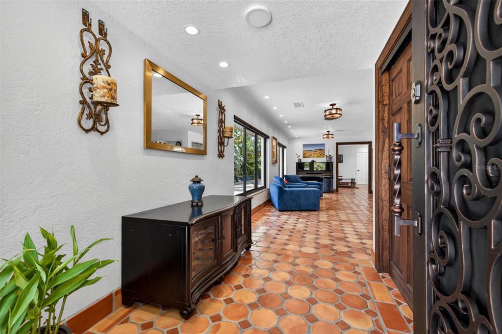 An entryway with terracotta tile flooring, a black console table, and a decorative metal door — 6213 12TH AVENUE S, GULFPORT, FL