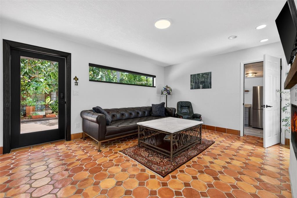 A living room features terracotta tile flooring, a dark leather sofa, and a glass door — 6213 12TH AVENUE S, GULFPORT, FL