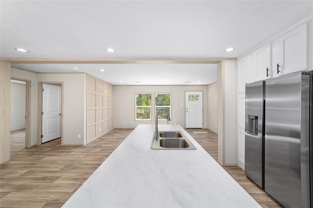 A kitchen island with a sink sits in front of a white-walled living area — 14830 SE 21ST PLACE, MORRISTON, FL
