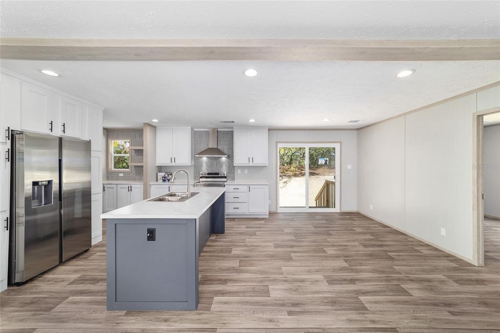 A modern kitchen features white cabinets, a blue island, stainless steel appliances, and wood flooring — 14830 SE 21ST PLACE, MORRISTON, FL