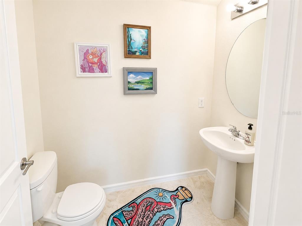 A small bathroom features a pedestal sink, a toilet, and three framed wall pictures — 1959 SUMMER SERENITY DRIVE, KISSIMMEE, FL