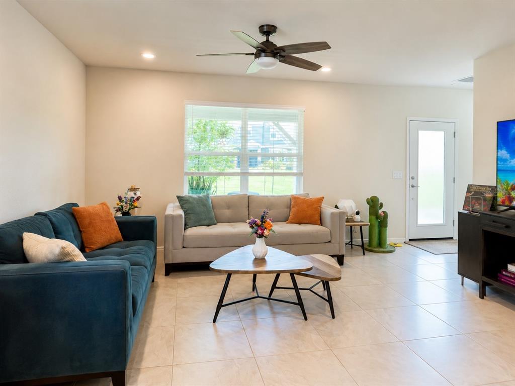 A living room features a blue sofa, a beige sofa, and a nested coffee table — 1959 SUMMER SERENITY DRIVE, KISSIMMEE, FL