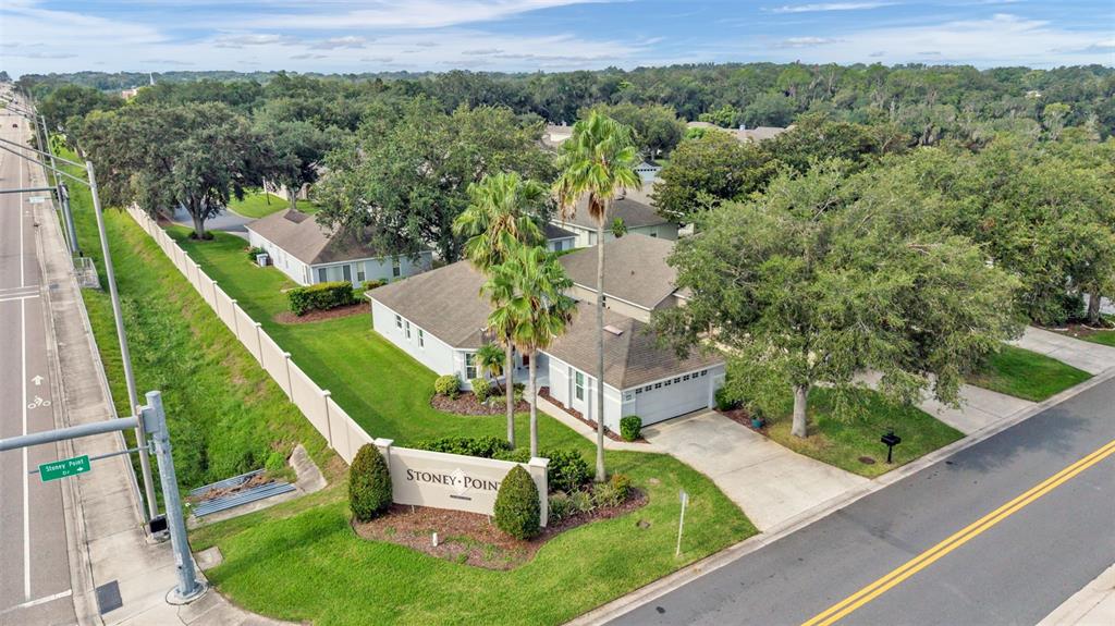 A single-story house with a gray garage door, concrete driveway, and surrounding green lawn — 2175 STONEY POINTE DRIVE, LAKELAND, FL
