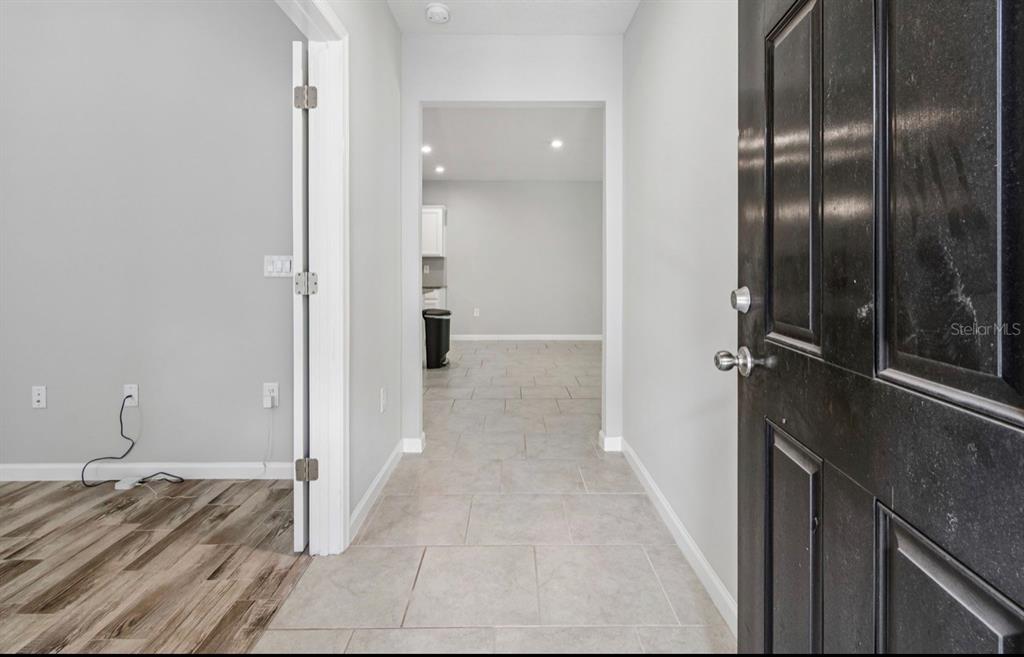 A view from an open doorway into a hallway with tile flooring and gray walls — 18307 TURNING LEAF CIRCLE, LAND O LAKES, FL