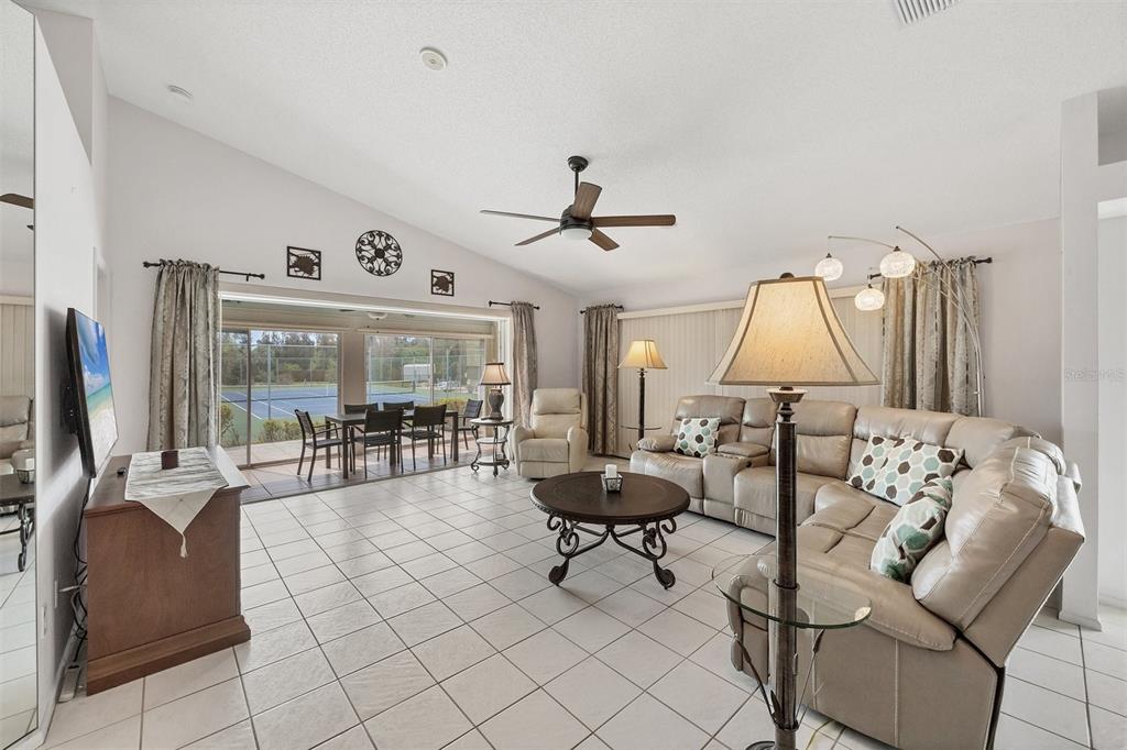 A living room with tile floors, a sectional sofa, and sliding doors overlooking a tennis court — 14281 PALM TERRACE, PORT CHARLOTTE, FL