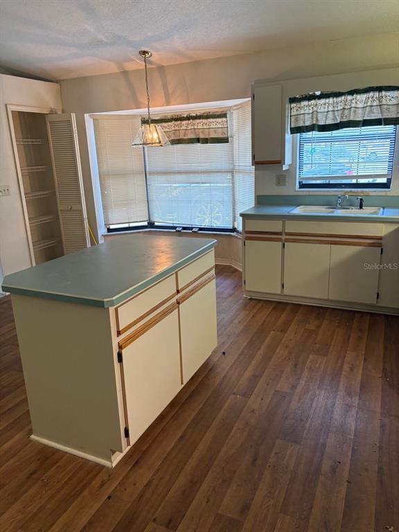A kitchen with a center island, light-colored cabinets, teal countertops, and a bay window — 222 MEADOW LAKE DRIVE, EDGEWATER, FL
