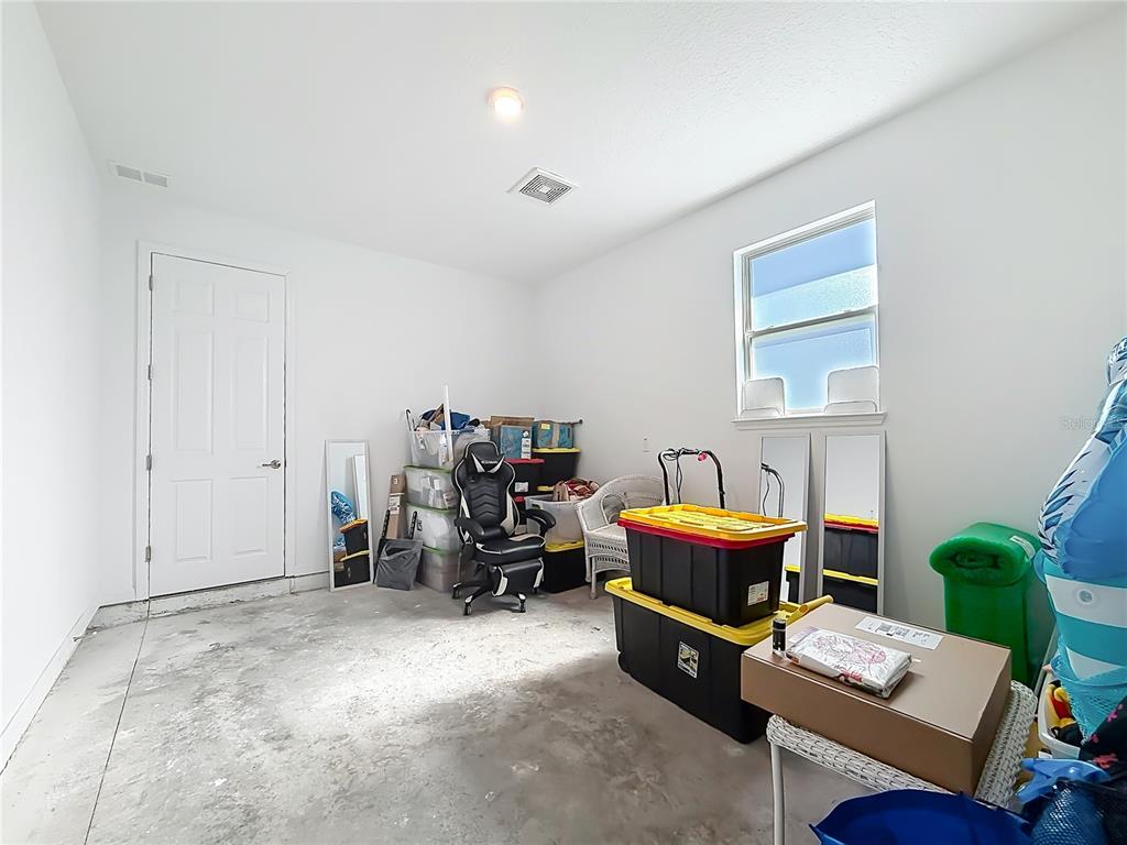 A garage with white walls, a concrete floor, a window, and various storage items — 7429 SW 61ST STREET, OCALA, FL
