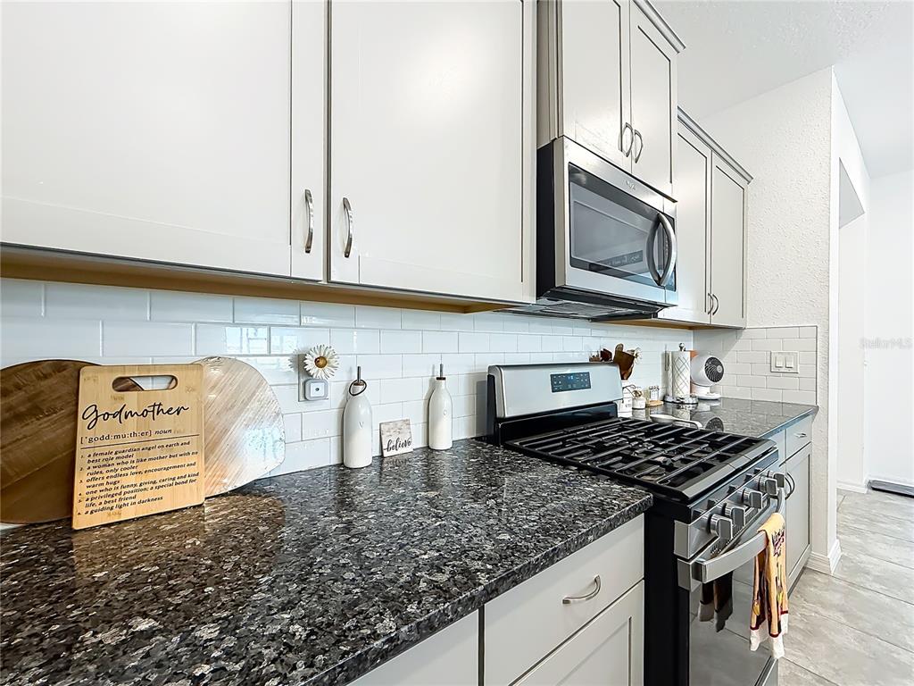 A kitchen features light gray cabinets, a dark granite countertop, and a white subway tile backsplash — 7429 SW 61ST STREET, OCALA, FL