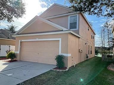 A two-story, tan-colored house features a two-car garage and a small front yard — 3449 HERON ISLAND DRIVE, NEW PORT RICHEY, FL