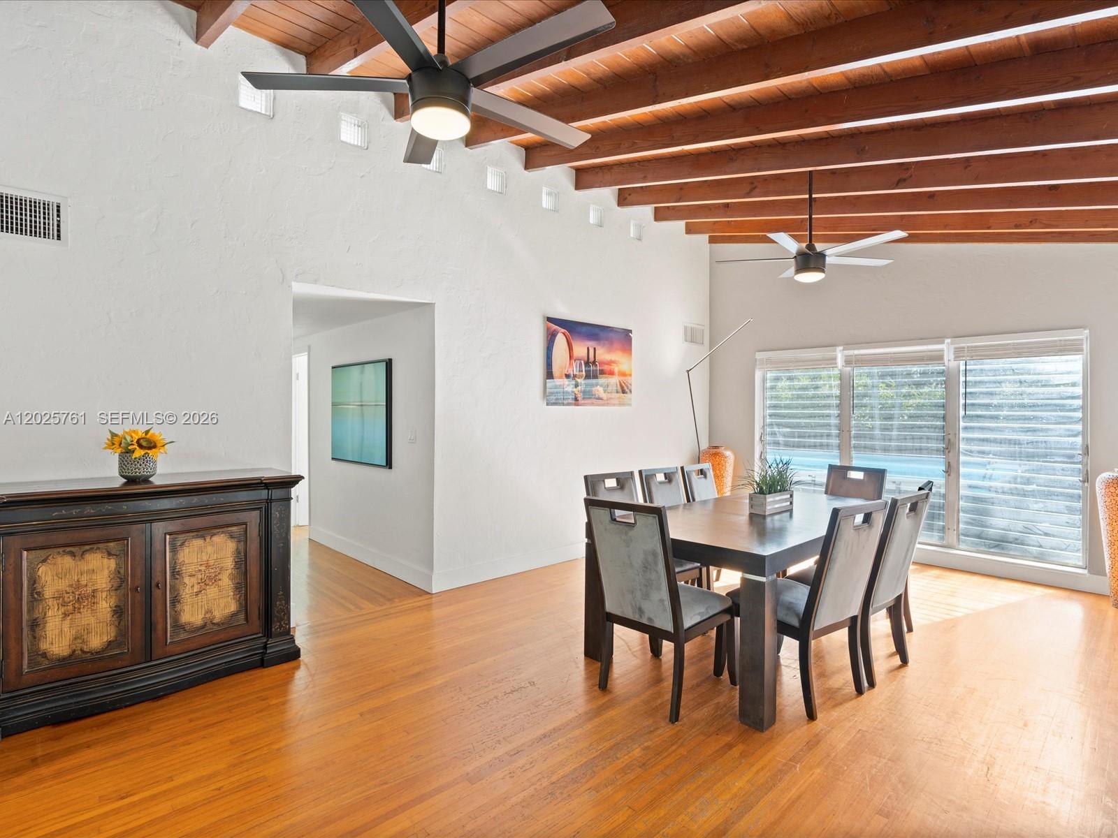 A dining room features a wooden beamed ceiling, hardwood floors, and two ceiling fans — 3981 SW 58th St, Dania Beach FL 33312, DANIA BEACH, FL