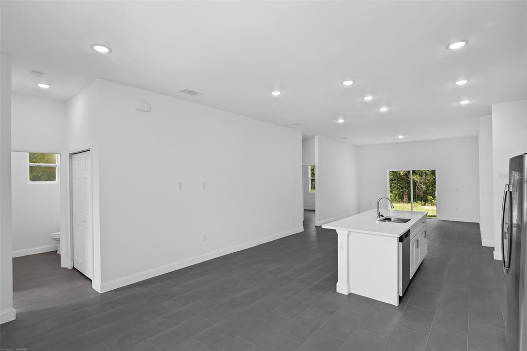 An open-concept kitchen and living area with white walls, gray tile floors, and a kitchen island — 22403 SW RAINBOW LAKES BOULEVARD, DUNNELLON, FL