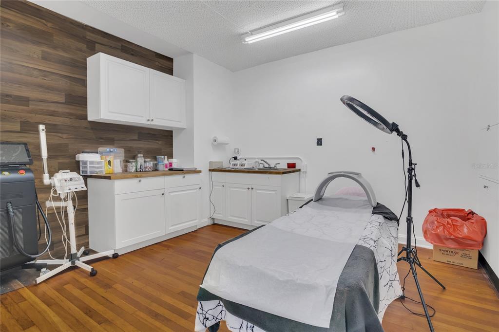 This treatment room features white cabinetry, wood-look flooring, a massage table, and medical equipment — 120 S DILLARD STREET, WINTER GARDEN, FL