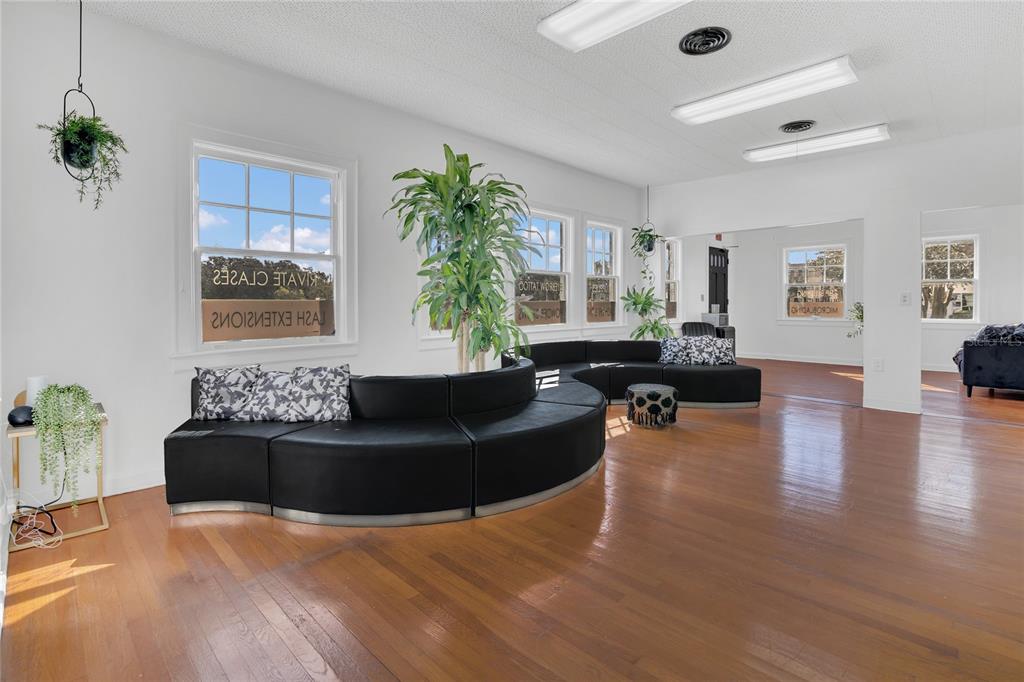 A bright, open waiting room features hardwood floors, a large curved black sofa, and plants — 120 S DILLARD STREET, WINTER GARDEN, FL